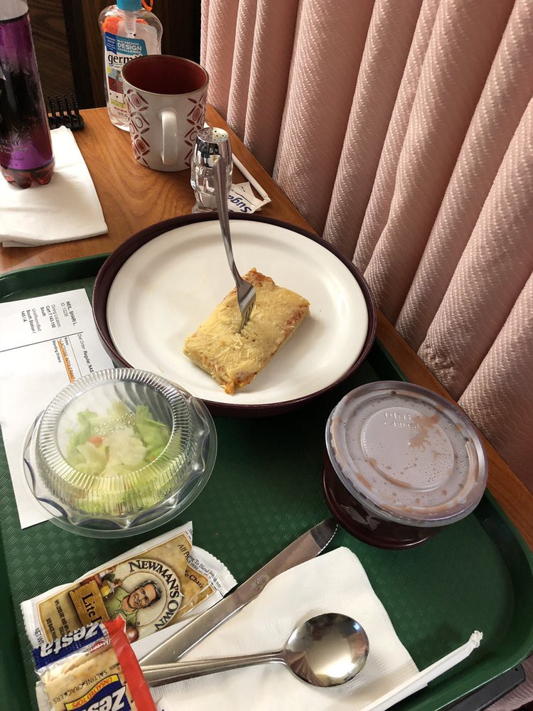 A meal on a tray includes a plated dish, salad, and a drink.