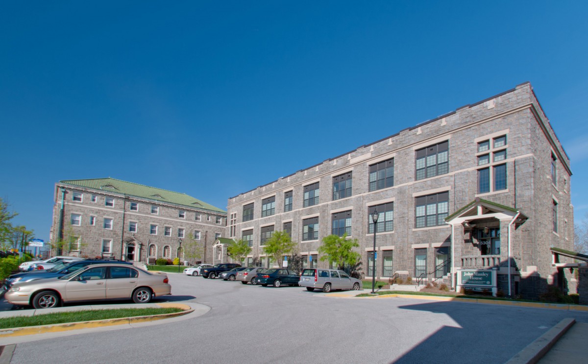 A modern building with a parking lot and cars under a clear blue sky.