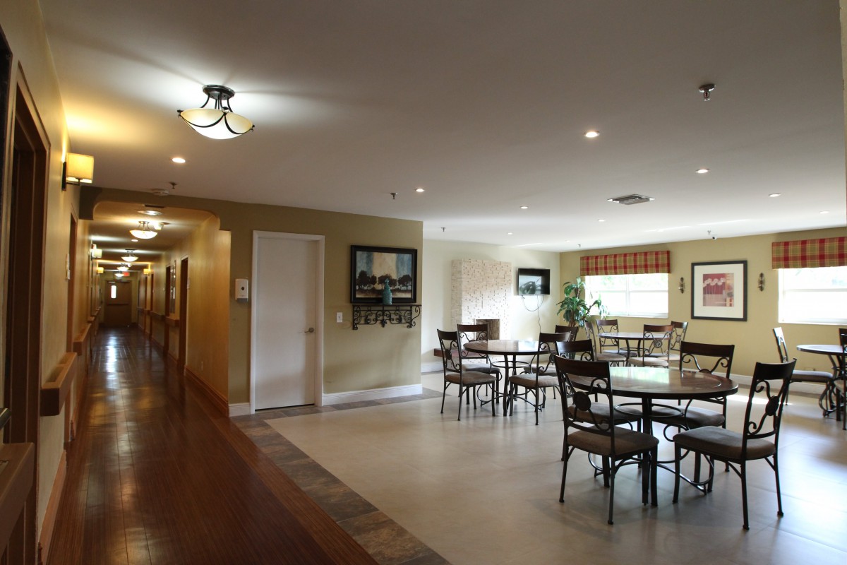 A spacious dining area with multiple tables and chairs adjacent to a hallway.