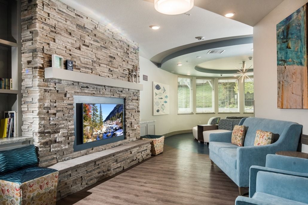A modern living room featuring a stone accent wall with a mounted television, cozy seating area, and elegant wood flooring.