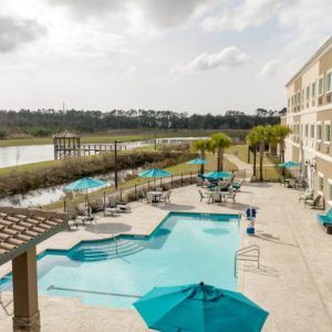 A hotel resort featuring a swimming pool area with lounge chairs and umbrellas, overlooking a scenic river view.