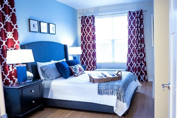 A cozy bedroom with blue walls and red patterned curtains.