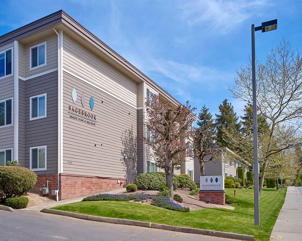 The exterior of a hotel building with well-maintained landscaping and clear signage on a sunny day.