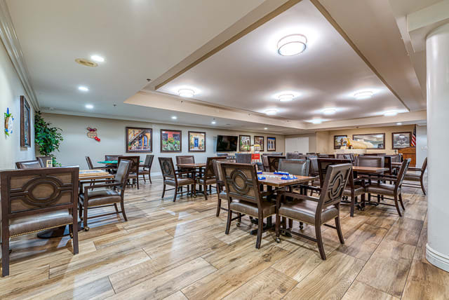 A spacious, well-lit dining area with wooden tables and chairs, decorated with artwork on the walls.