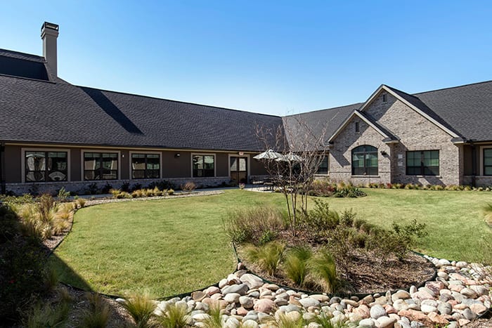 A spacious house with a well-maintained garden and lawn under a clear blue sky.