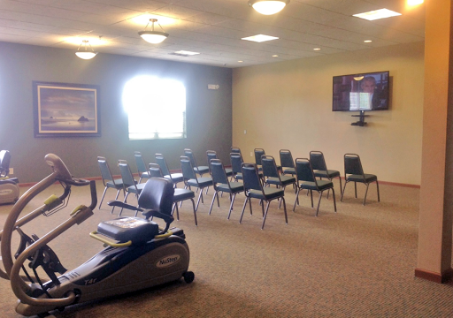 A spacious waiting room with chairs arranged neatly and exercise equipment in the corner.