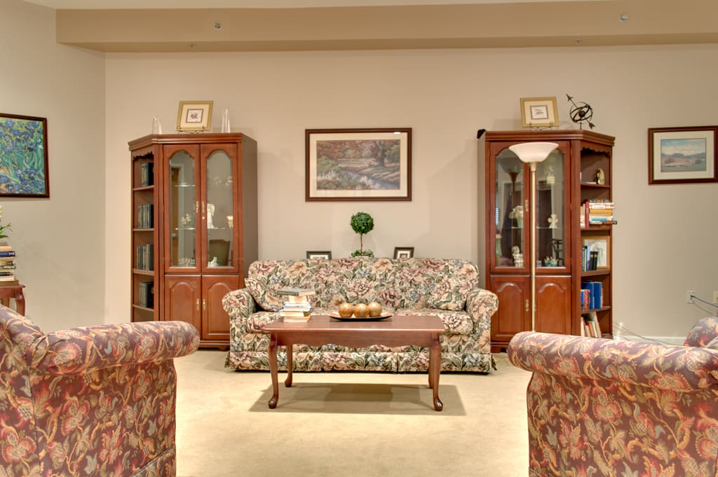 A cozy living room with a floral sofa, wooden cabinets, and a coffee table.