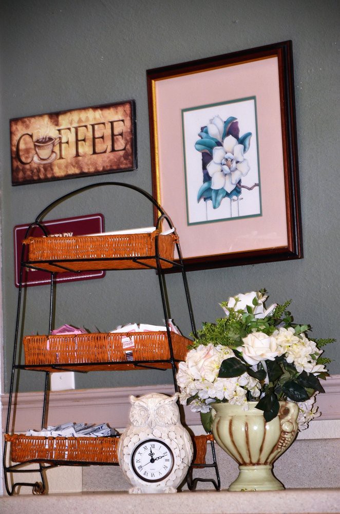 A cozy corner featuring a coffee-themed decor, wicker shelves, and floral arrangements.