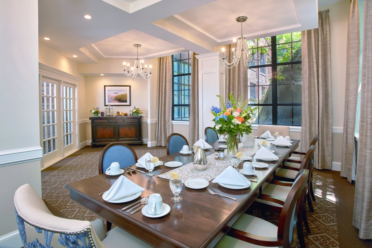 A beautifully set formal dining room with an elegant table arrangement and chandelier.