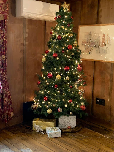 A beautifully decorated Christmas tree with lights and ornaments, surrounded by wrapped presents.
