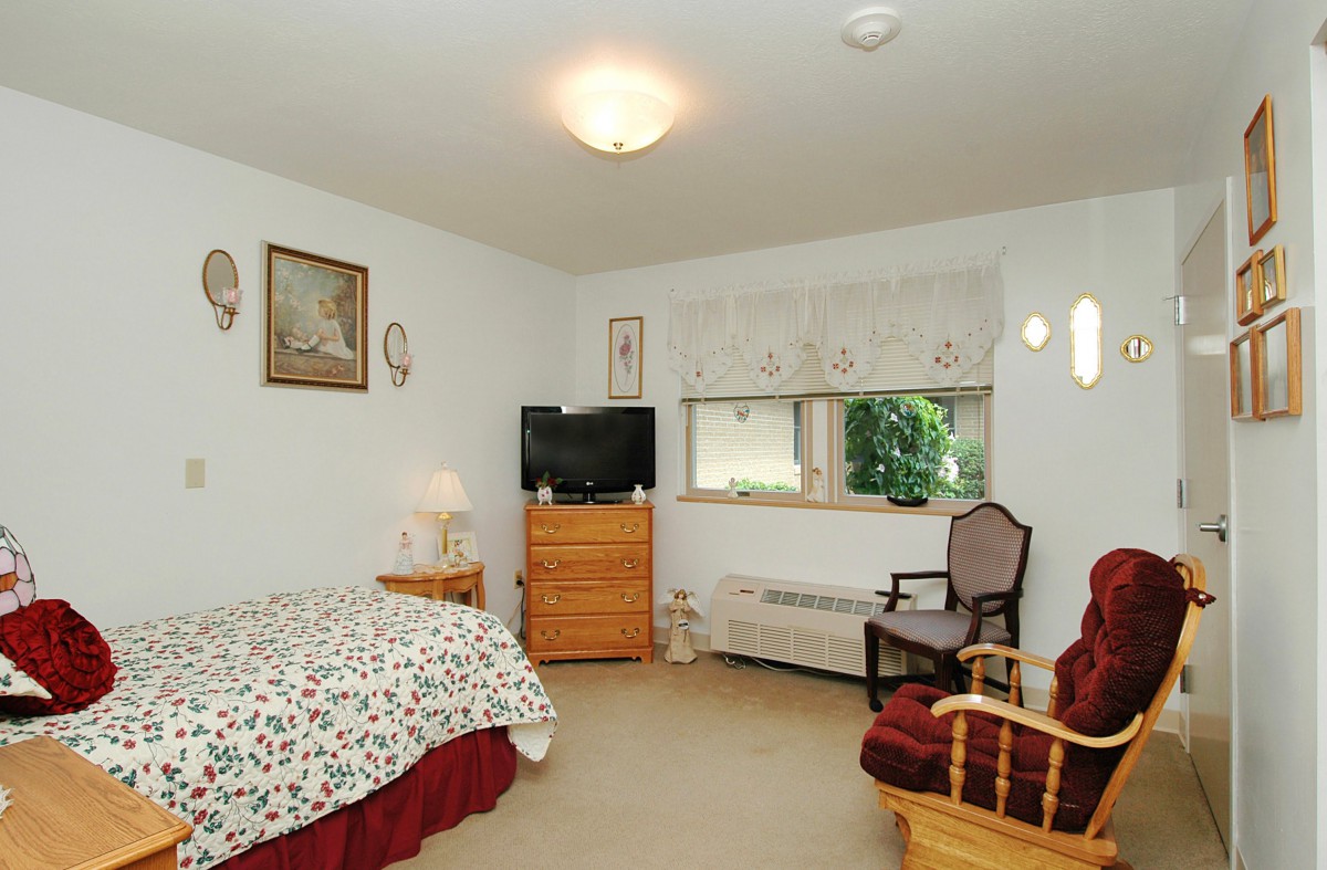 A cozy bedroom with a bed, television, and various furnishings.