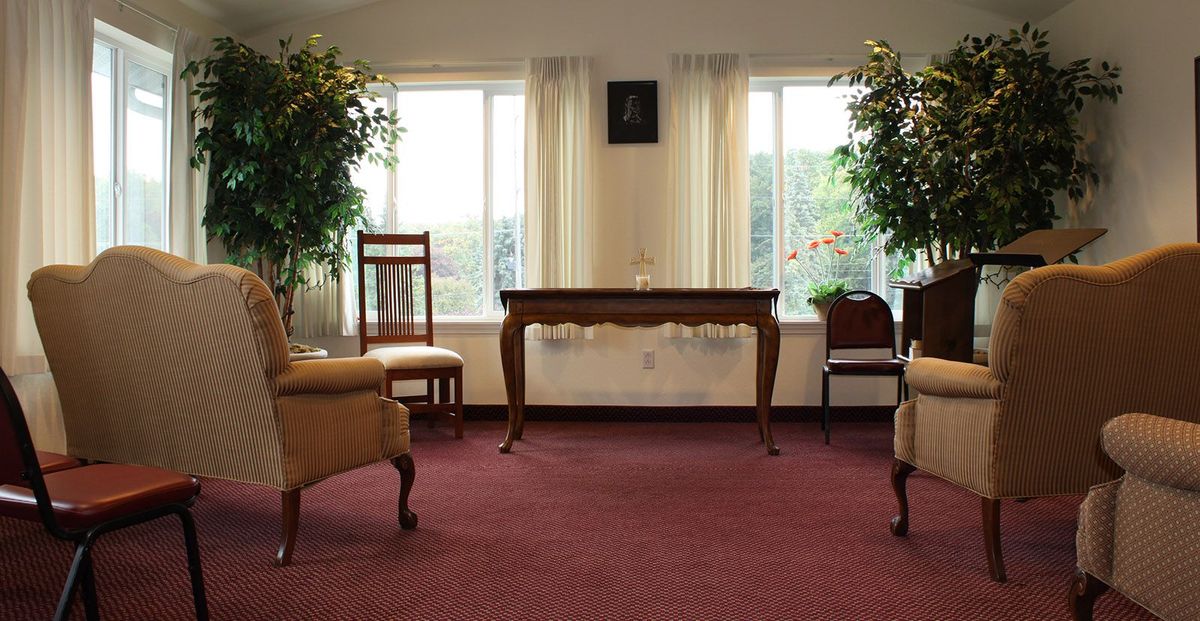 A cozy living room with elegant furniture, large windows, and lush greenery.
