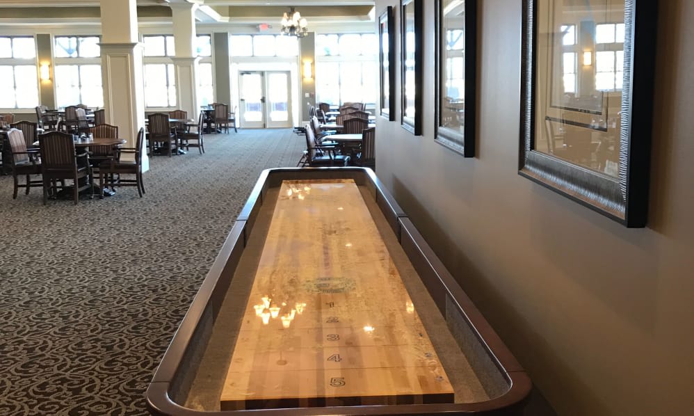 An indoor shuffleboard table in a spacious game room setting.