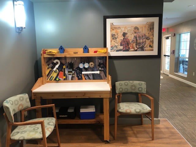 A cozy office nook with a wooden desk and chairs, adorned with a painting on the wall.