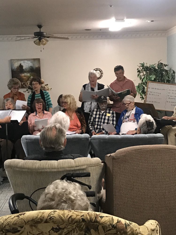 A group of seniors performing a song in front of an audience in a cozy indoor setting.