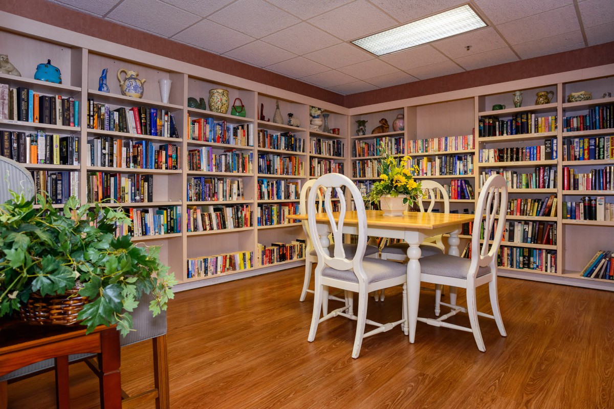 A cozy library corner with bookshelves and a table set for reading.