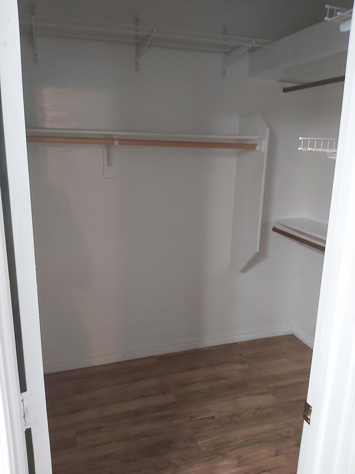 An empty walk-in closet with wooden flooring and built-in shelves.