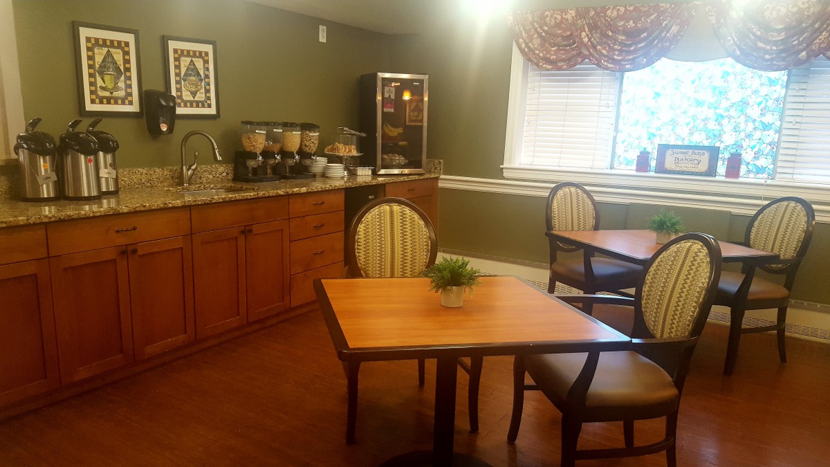 Cozy dining area with a coffee station, wooden tables, and striped chairs.