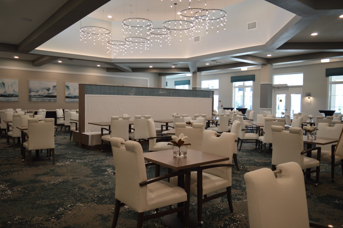 A modern and elegant dining area with chandeliers and neatly arranged tables and chairs.
