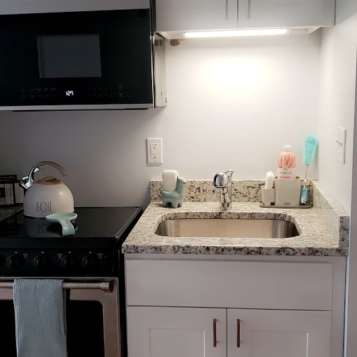 A modern kitchen setup featuring a sink, stove, and microwave with a sleek granite countertop.