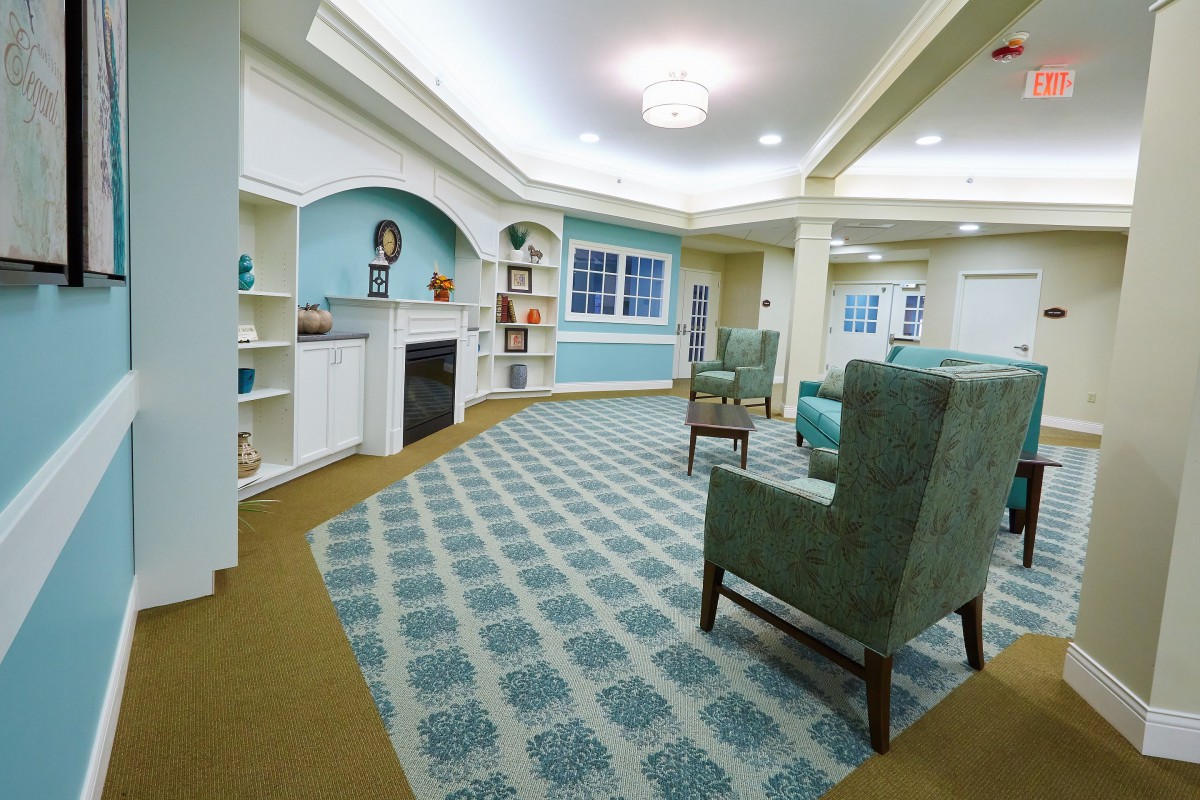 A cozy living room with elegant furniture, a fireplace, and patterned carpet.