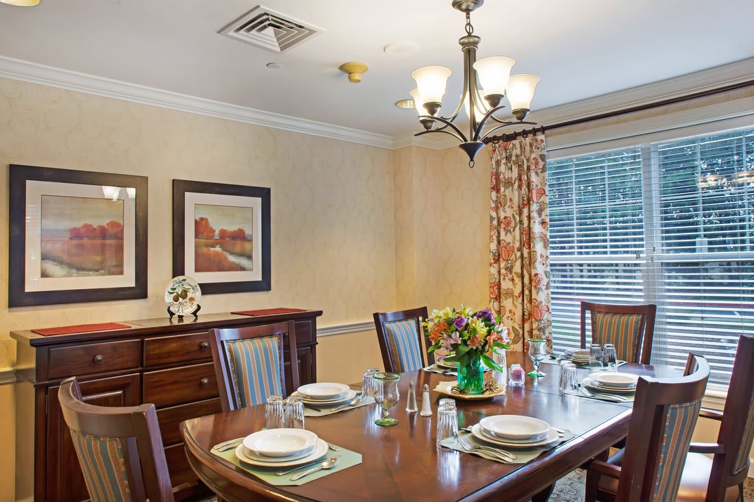 A well-appointed dining room with a set table, elegant chandelier, and tasteful artwork.