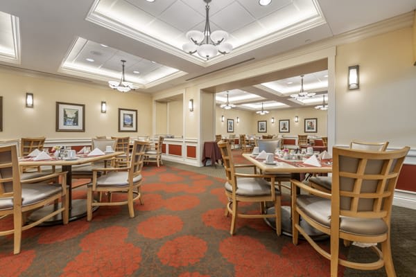 A spacious and elegantly designed restaurant dining area with tables and chairs arranged neatly under ornate chandeliers.