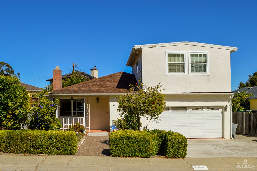 A suburban two-story house with a garage and well-maintained shrubs.