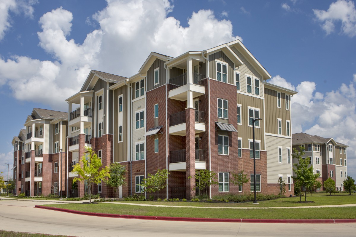 A modern multi-story apartment building with balconies and a mix of materials in its design.