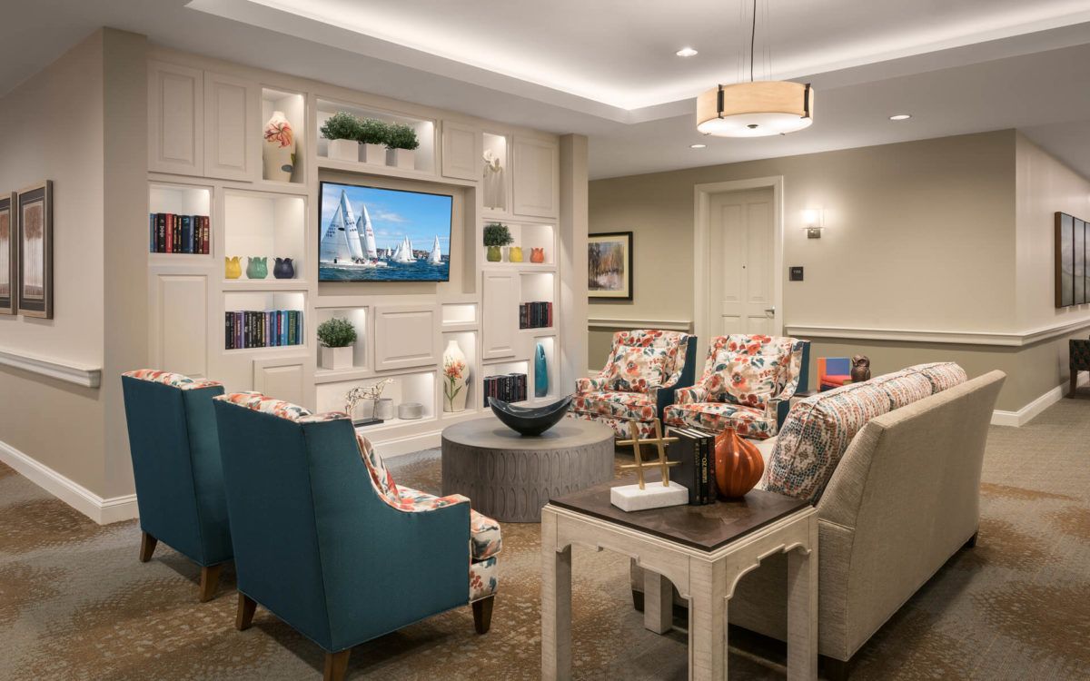 A modern living room with comfortable armchairs, decorative shelves, and a wall-mounted television.