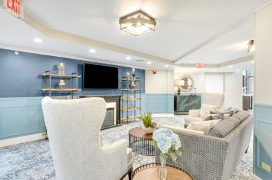 A modern living room with stylish furniture, a fireplace, and a large TV on a blue-accented wall.