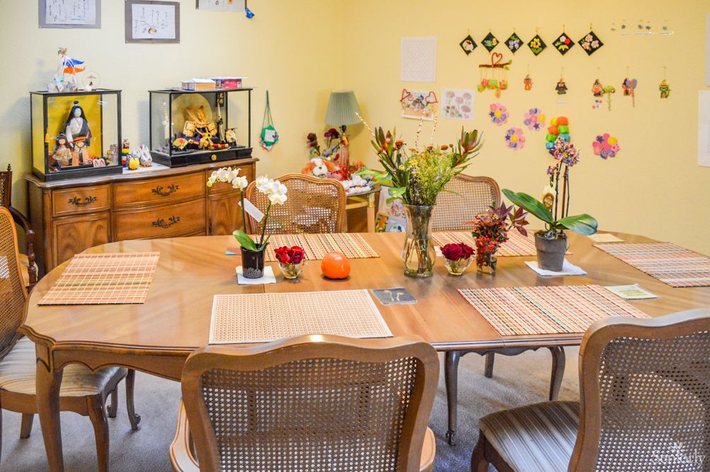 A cozy dining room with a wooden table, adorned with fresh flowers and colorful decorations on the walls.