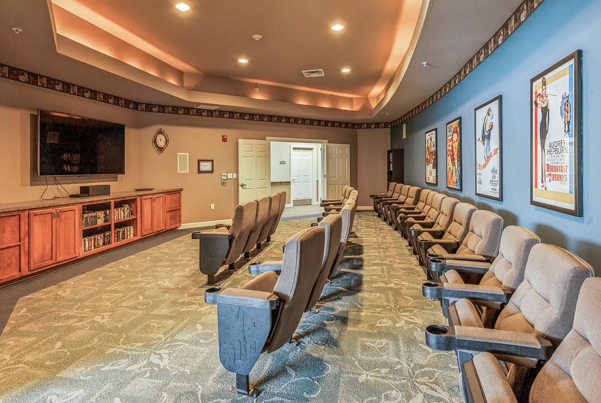 An empty theater room with rows of seats and movie posters on the walls.