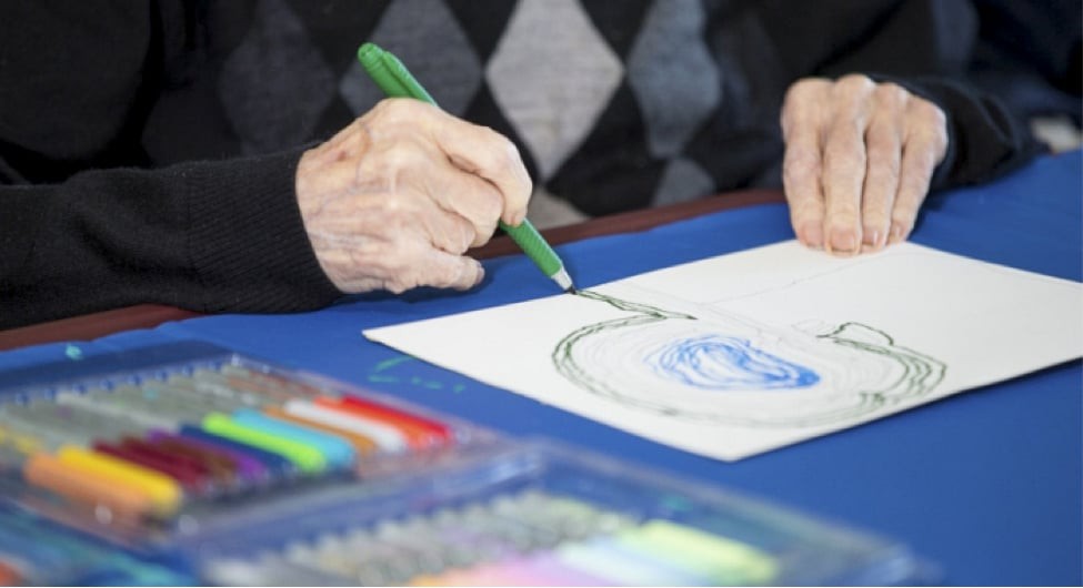 A person drawing with colored pencils on a piece of paper.