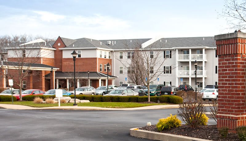 A suburban residential building with a parking lot in front.