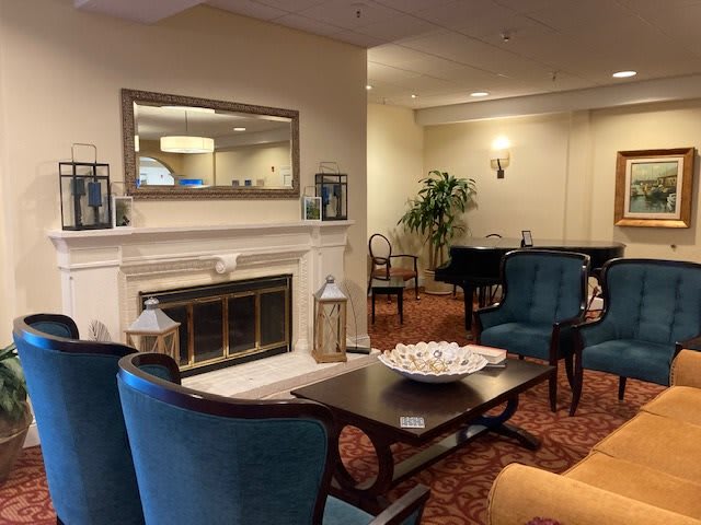 A cozy lounge area featuring comfortable seating, a fireplace, and a piano.