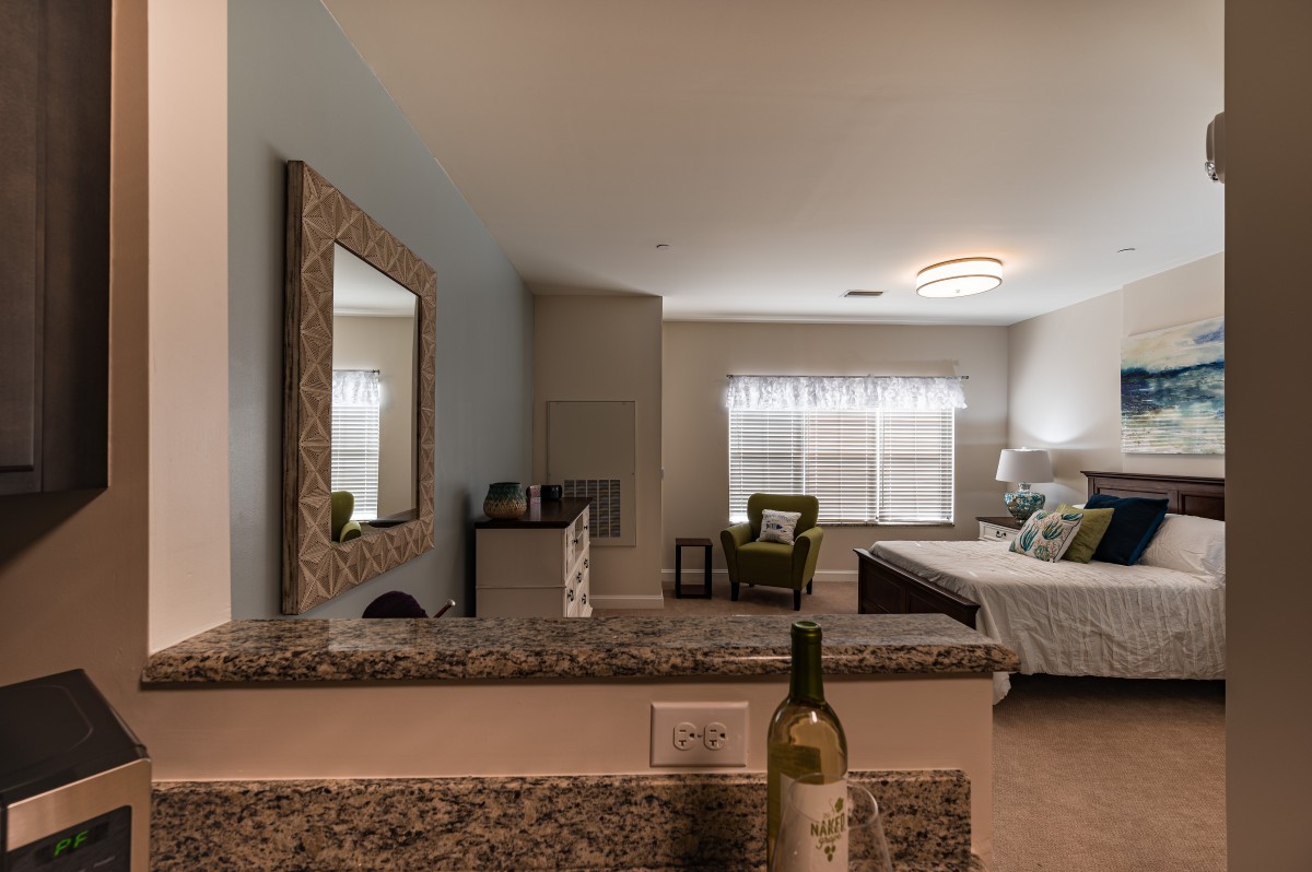 Modern bedroom interior with a bed, mirror, and seating area.