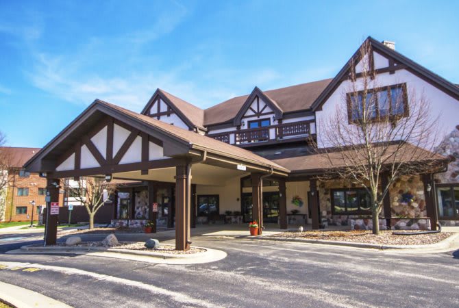 A tudor-style building with a covered entrance and adjacent parking lot.