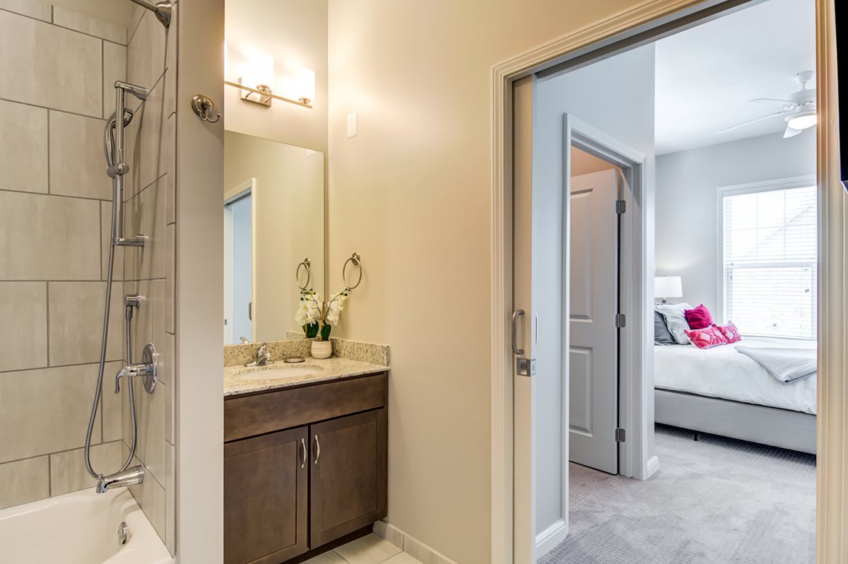 A modern bathroom with a vanity and sink, connected to a bedroom.