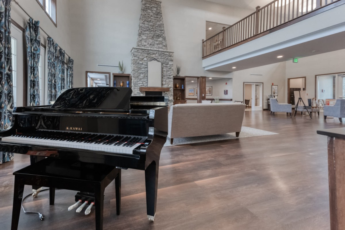 Modern living room with a grand piano and stone fireplace.