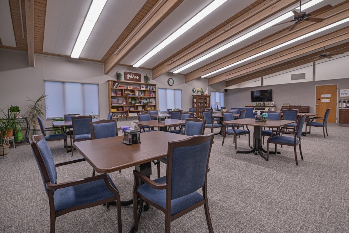 A spacious study area with numerous tables and chairs surrounded by bookshelves.