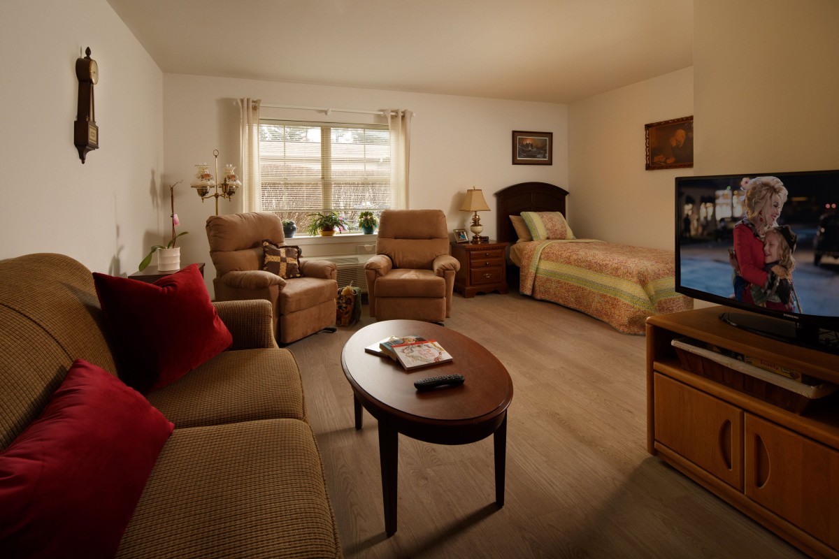 A cozy living and bedroom area featuring comfortable seating, a television, and a bed.