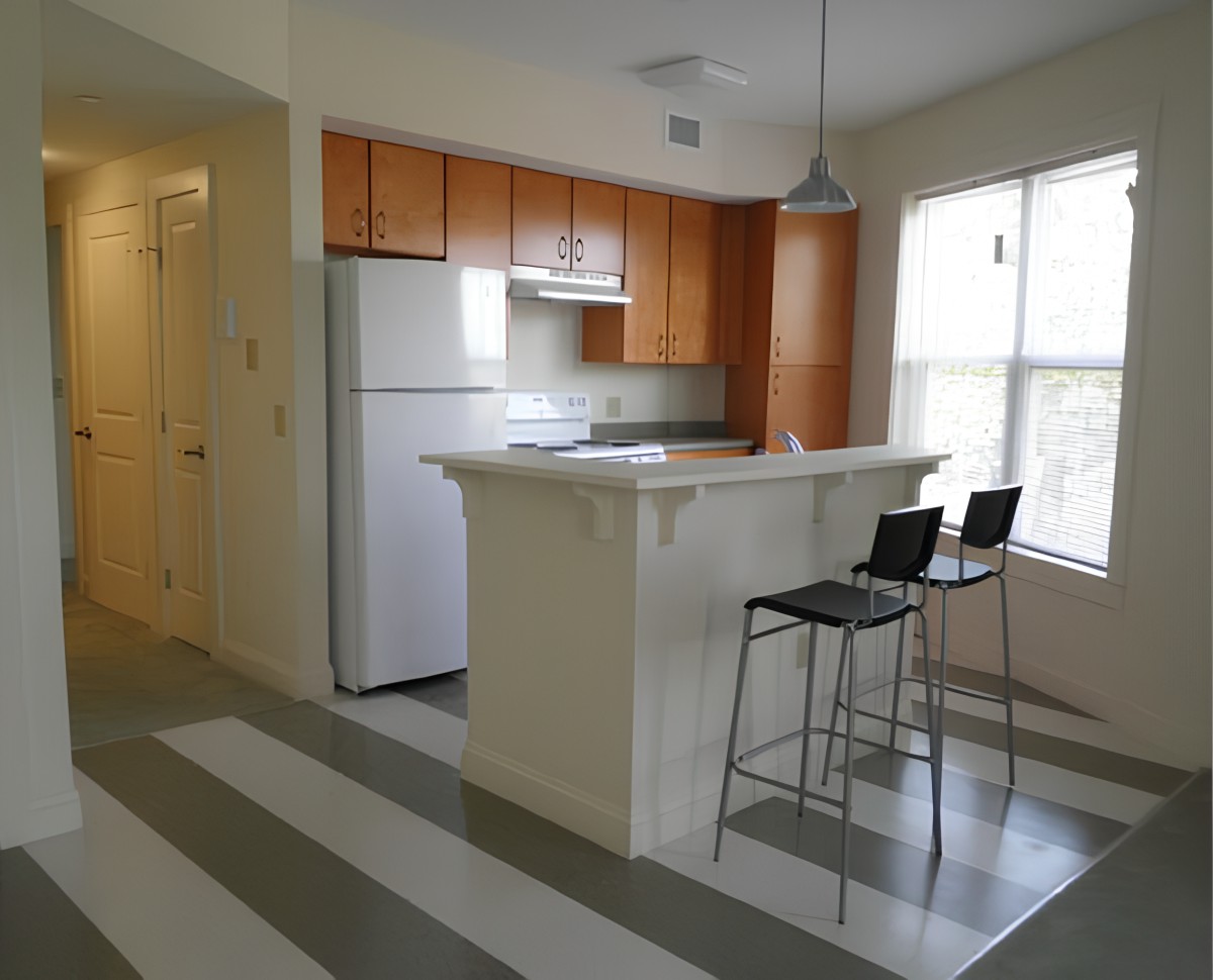 A modern apartment kitchen with a small breakfast bar and two bar stools.