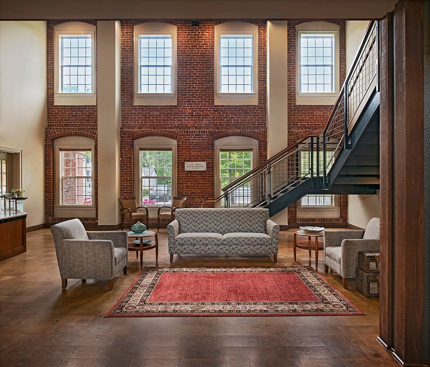 Spacious loft living room with brick walls, tall windows, and modern furniture.
