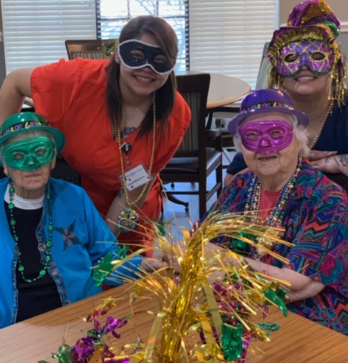 A group of people celebrating Mardi Gras wearing colorful masks and beads.