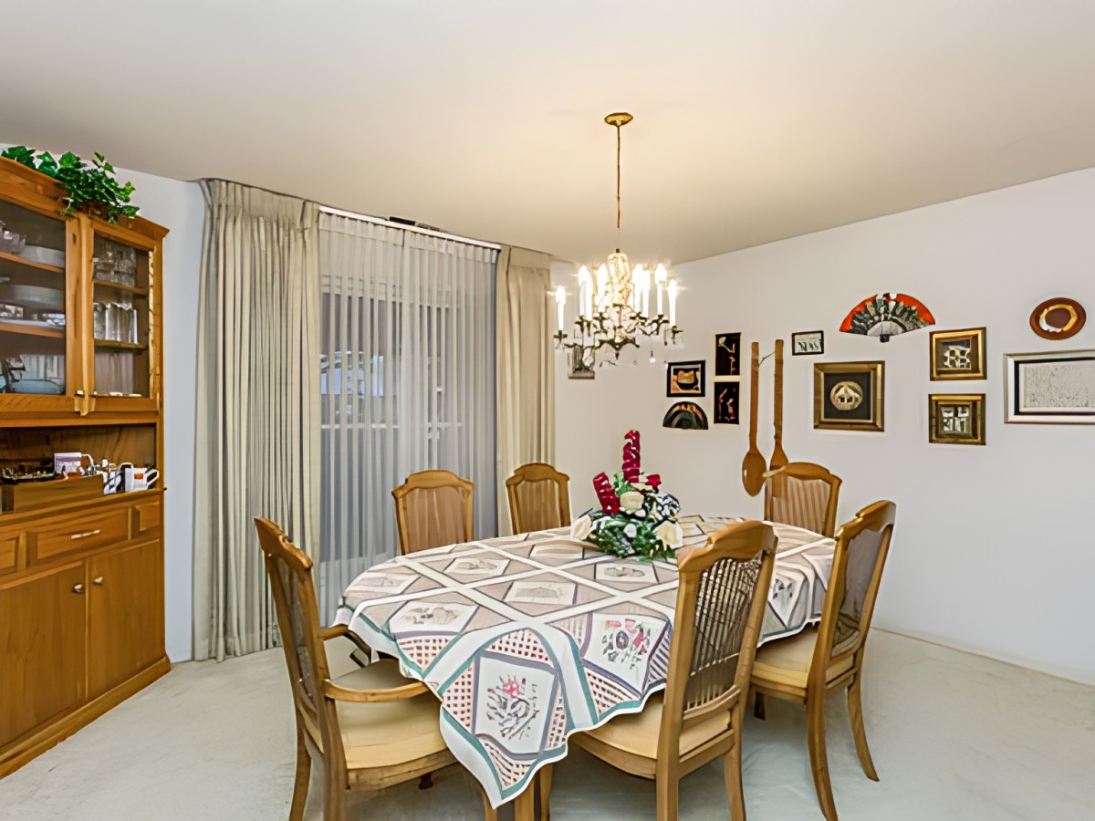 A classic styled dining room featuring a large table with six chairs and a chandelier above.