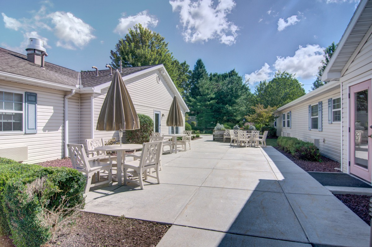A sunny outdoor patio with tables and umbrellas in a residential setting.