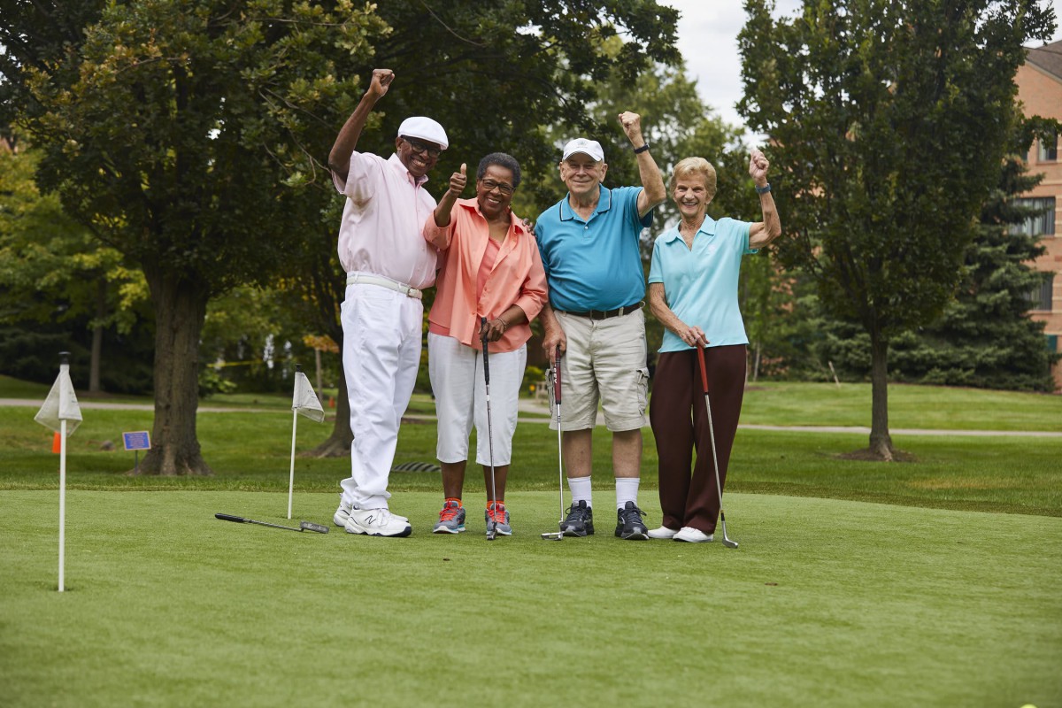 A group of four friends enjoying a day of golf on the green.