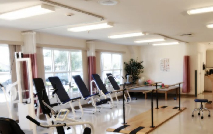 A rehabilitation center equipped with exercise benches and therapy parallel bars.