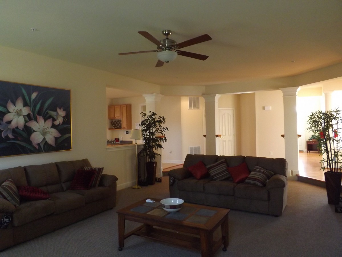 A cozy living room with two sofas, a coffee table, a ceiling fan, and wall artwork.